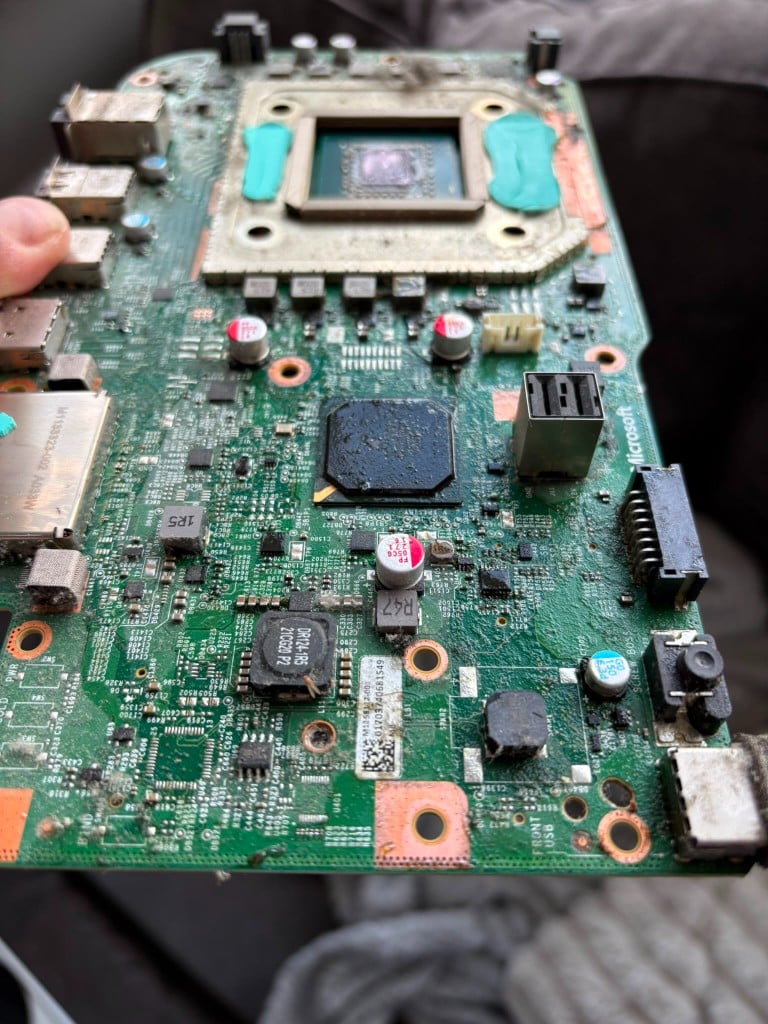 Xbox motherboard held for inspection with APU area visible
