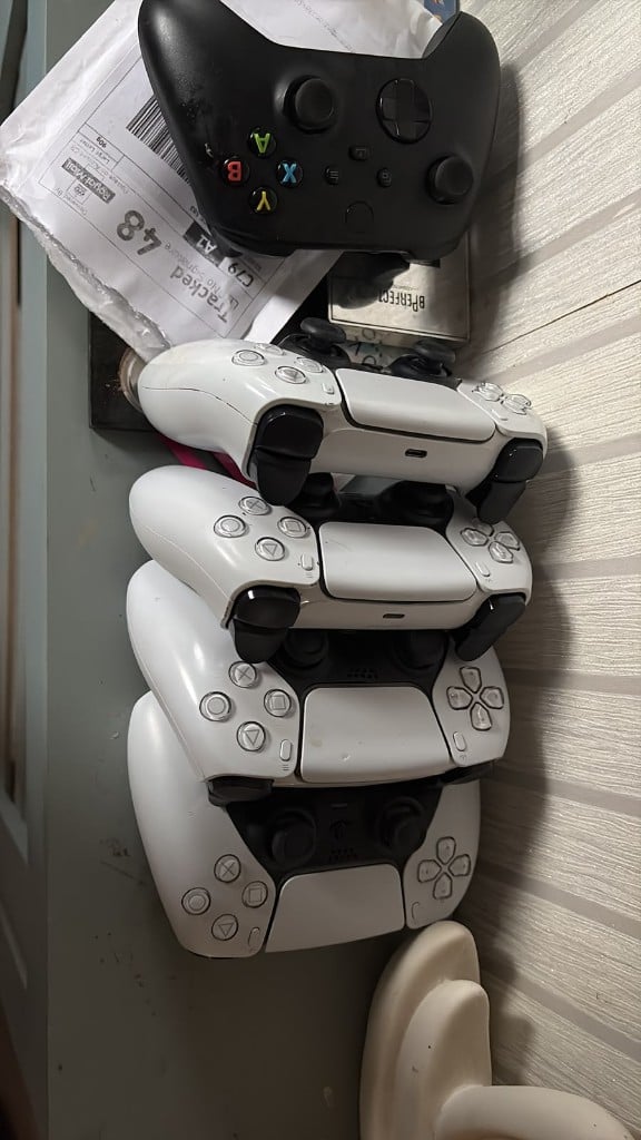Stack of DualSense and Xbox controllers beside Royal Mail packaging